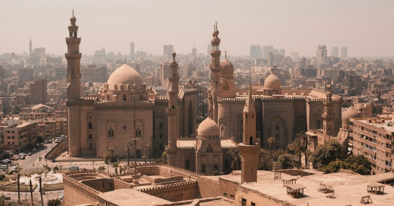 A bird's eye view of the Sultan Hassan Mosque and Al Rifai Mosque next door shows a series of minarets and domes with the buildings of the modern-day city right behind.